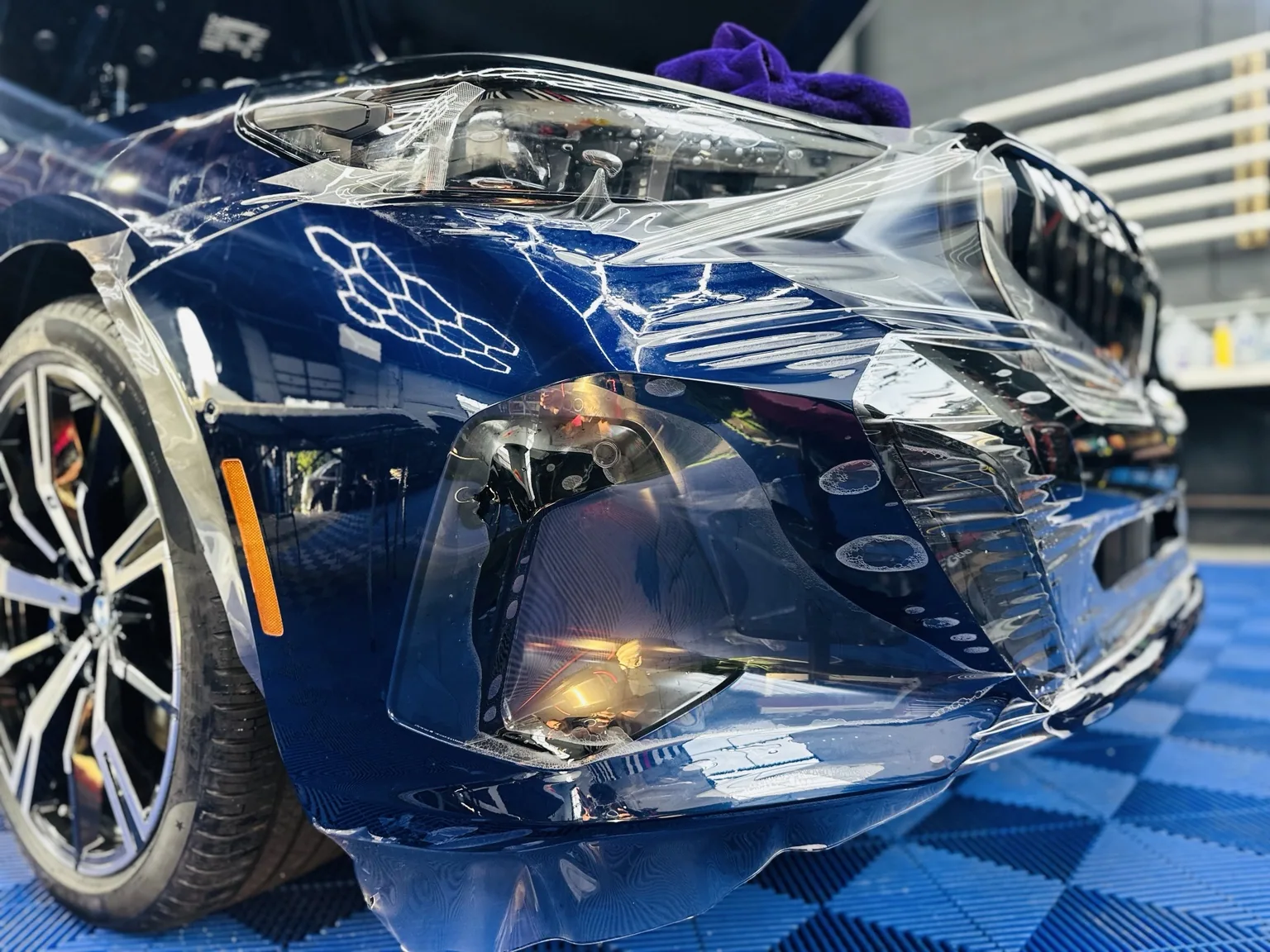 Clear paint protection film being applied to a blue vehicle
