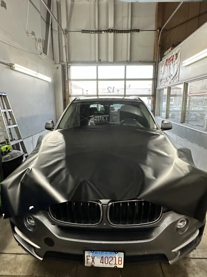 Black vinyl positioned over a vehicle hood.
